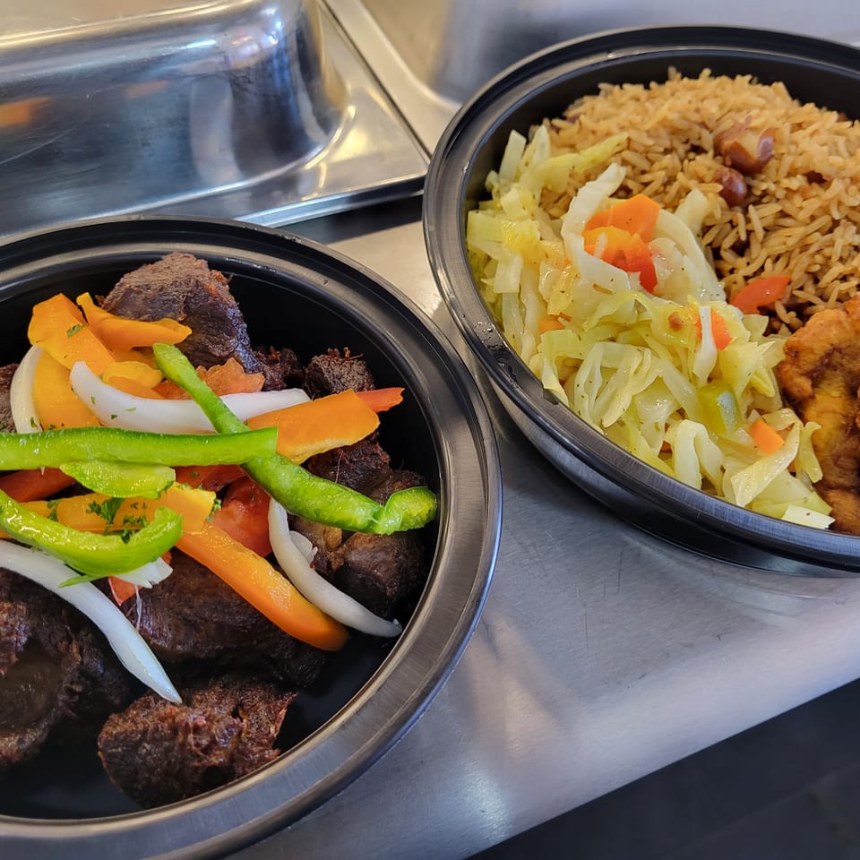 Two Haitian meals in black bowls: fried meat with peppers and rice with cabbage and plantains.