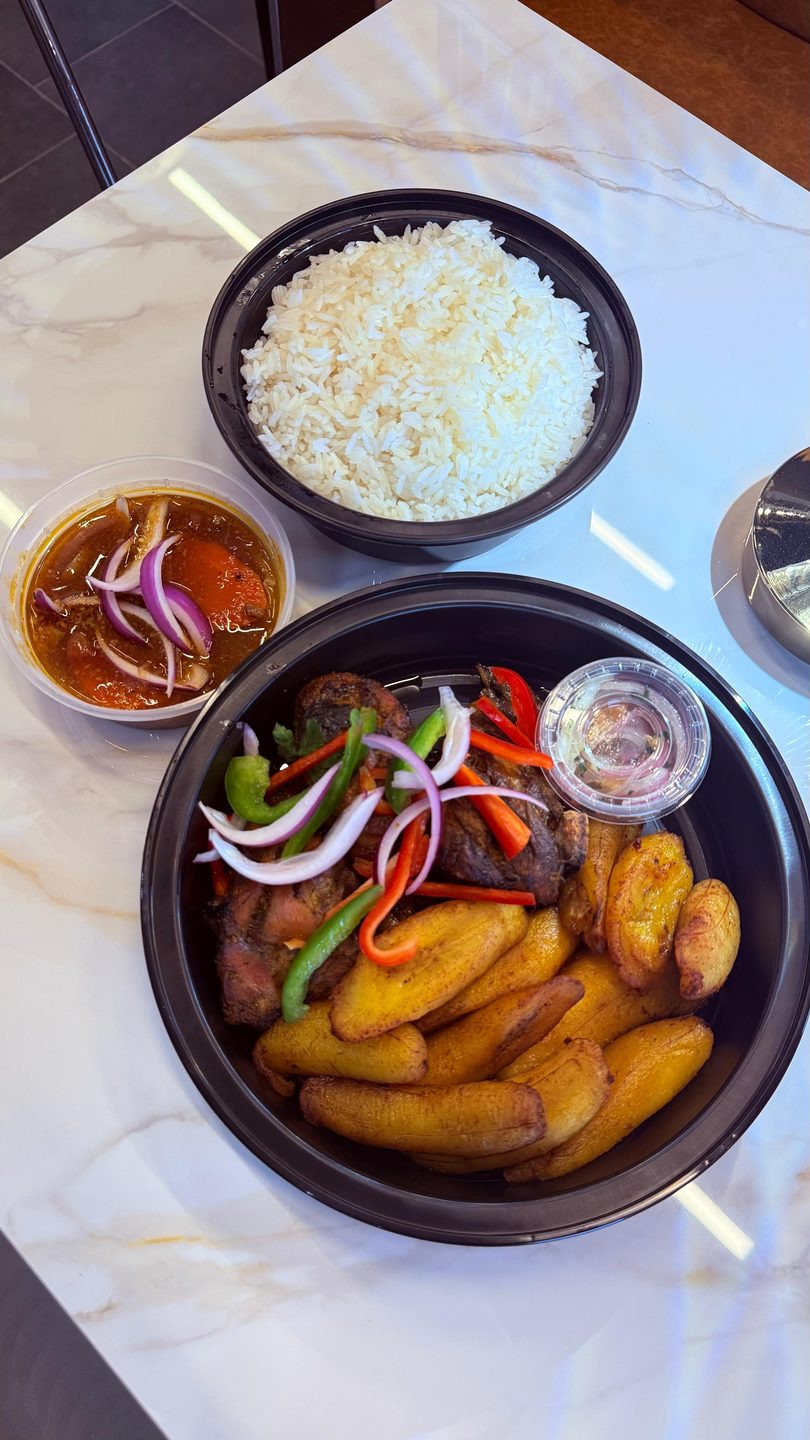 Haitian griot with fried plantains, rice, and a side of pikliz on a marble table.